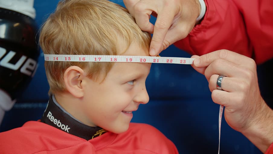 Un adulte mesurant la tête d'un enfant à l'aide d'un ruban à mesurer