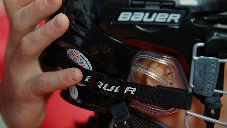 Close up of person tightening Bauer hockey helmet