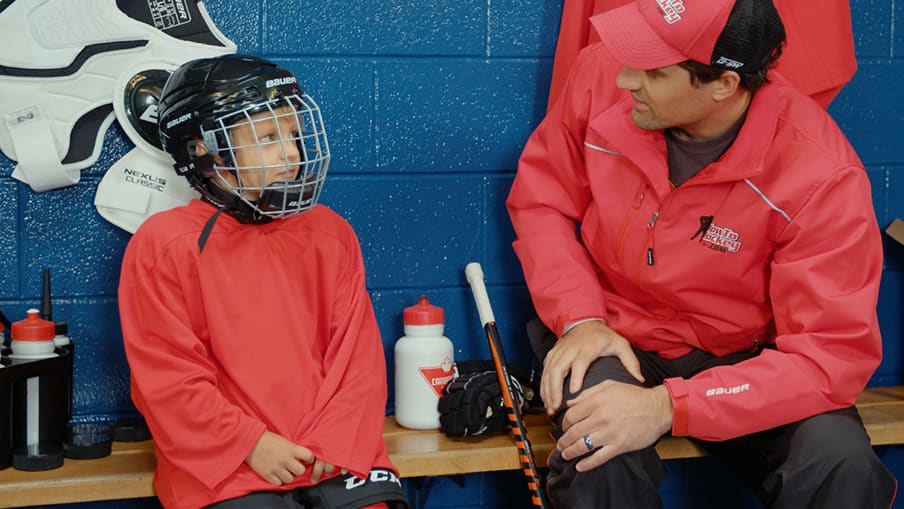 Hockey coach sitting beside child in hockey gear