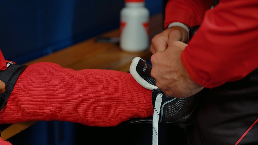 Un adulte laçant les patins de hockey d'un enfant