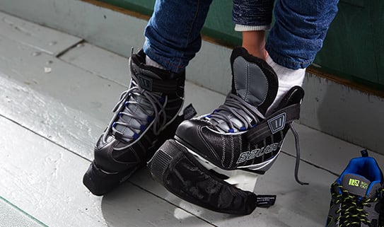 Person sitting down putting ice skates on