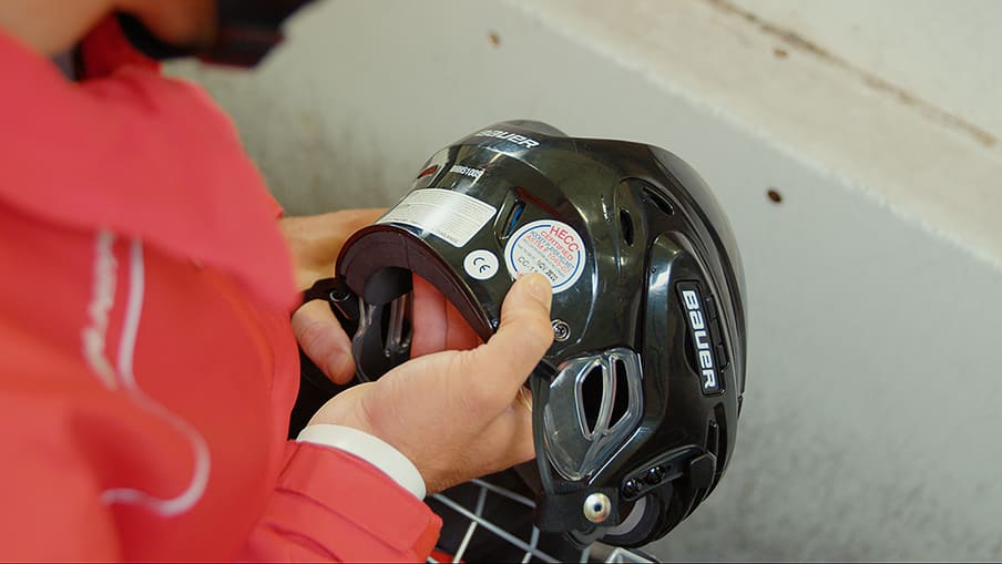 Person holding hockey helmet with sticker expiry date
