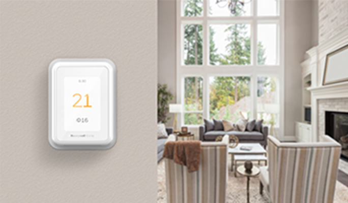 Un thermostat intelligent sur un mur affichant une température de 21°C à l'intérieur et de 16°C à l'extérieur.