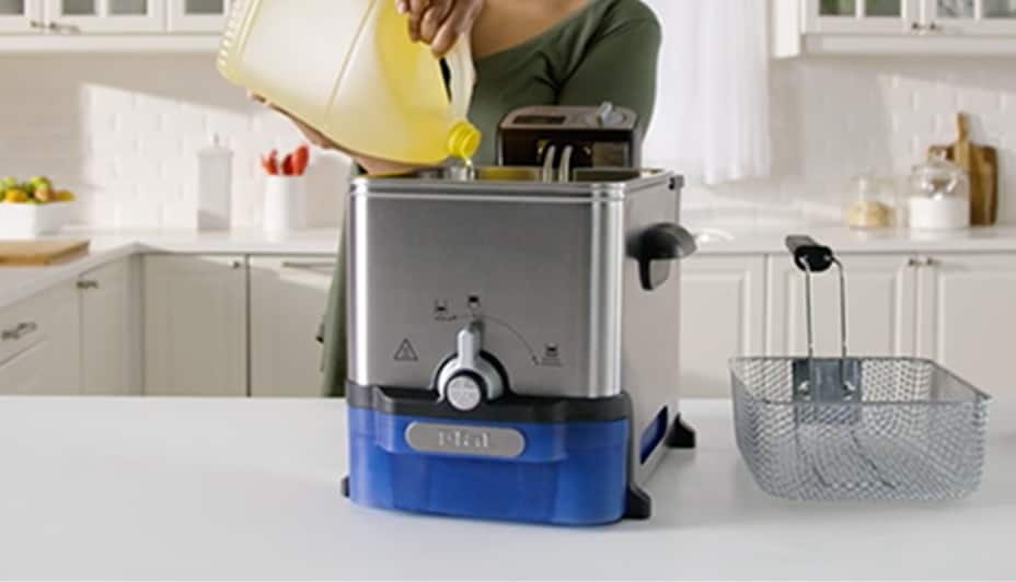 Une femme versant de l'huile dans une friteuse T-fal Ultimate EZ Clean.