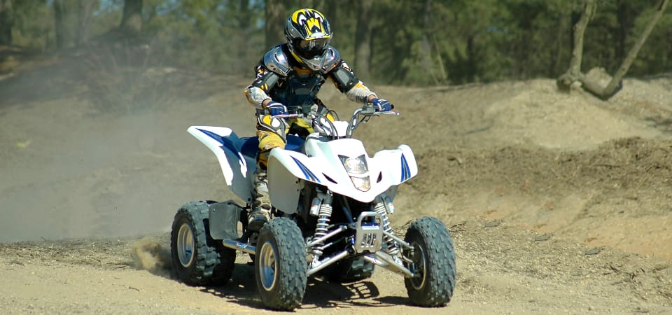 A person riding an ATV in a muddy terrain.