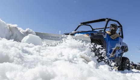 A person plowing snow with his ATV.
