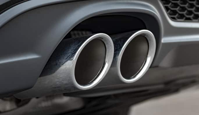 Close-up of a car’s exhaust pipe with dual chrome exhaust tips.
