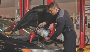 Man changing oil under hood of car