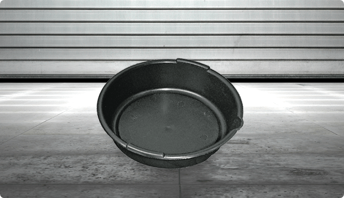 A round black drain pan in a garage setting.