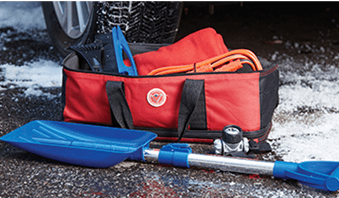 Road safety kit in a red bag with shovel, lights, and cables.