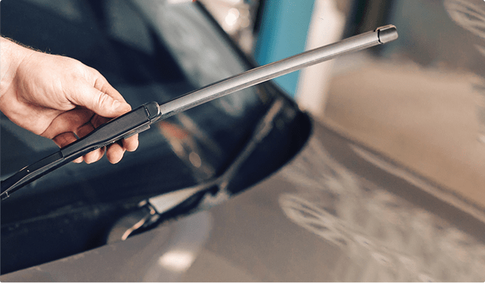 Person holds a wiper blade on a vehicle.
