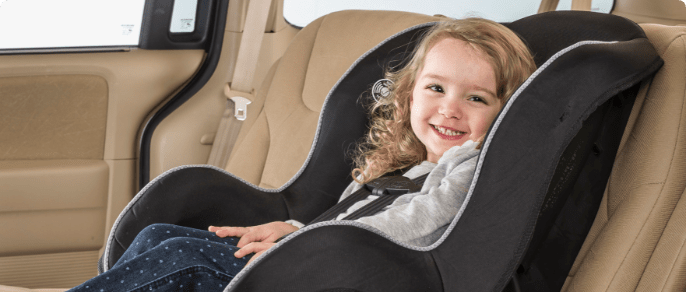 Smiling child buckled into a car seat.