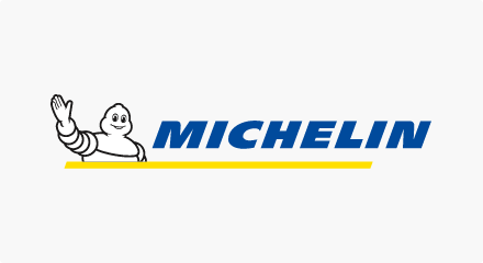 Le logo Michelin : Un dessin animé torse levé de la mascotte du Bonhomme Michelin à gauche d'un mot-symbole bleu « MICHELIN », le tout souligné d'un trait jaune.