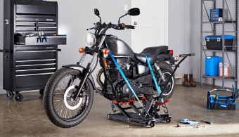 A motorcycle hoisted on a jack in a garage.