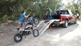 A father and son load their motorcycles into the back of a truck.