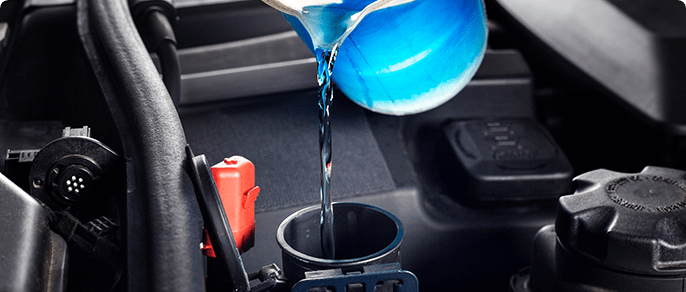 Versement de liquide de refroidissement dans le moteur d'un véhicule.