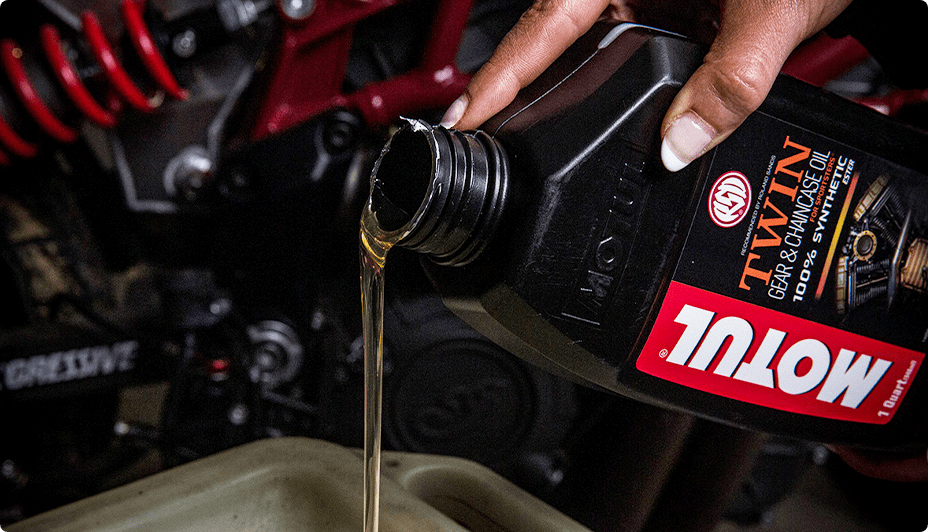Hand pouring Motul Oil from a bottle into an engine.