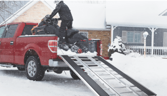 Snowmobile being loading onto truck.