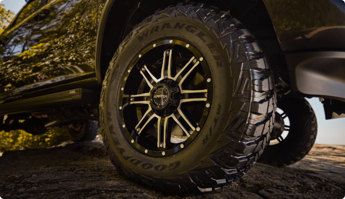A close-up of a gloss-black, machined Krank Shaft Wheel mounted on a black pickup truck.