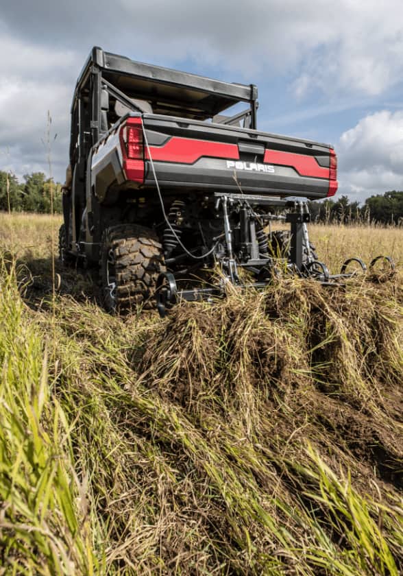 A farming vehicle raking crops in a field. 