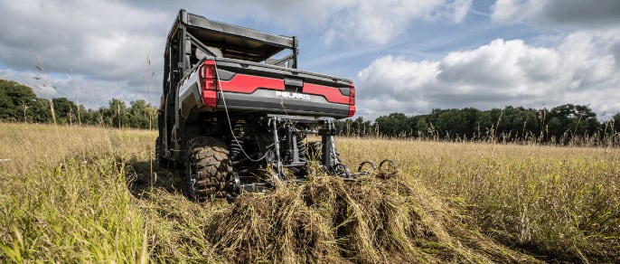 A farming vehicle raking crops in a field. 