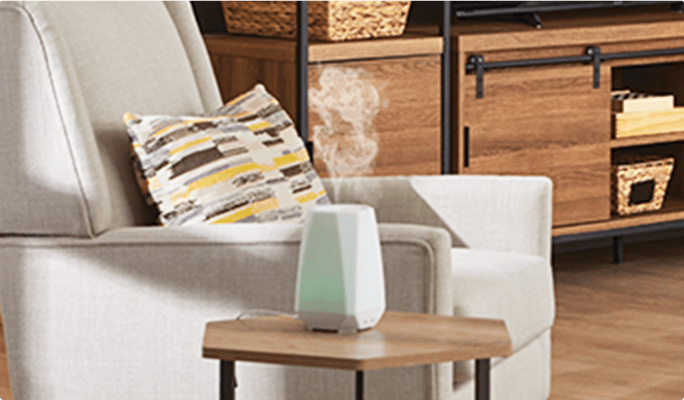 Essential oil diffuser on a side table next to an accent chair in a living room.