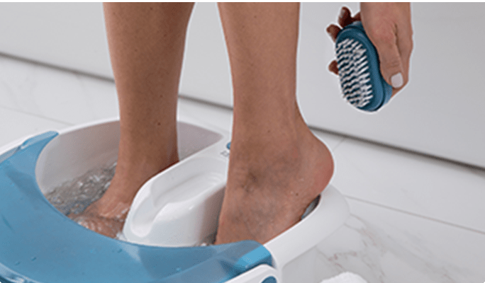 Une personne utilisant un spa pour les pieds bleu et blanc. 