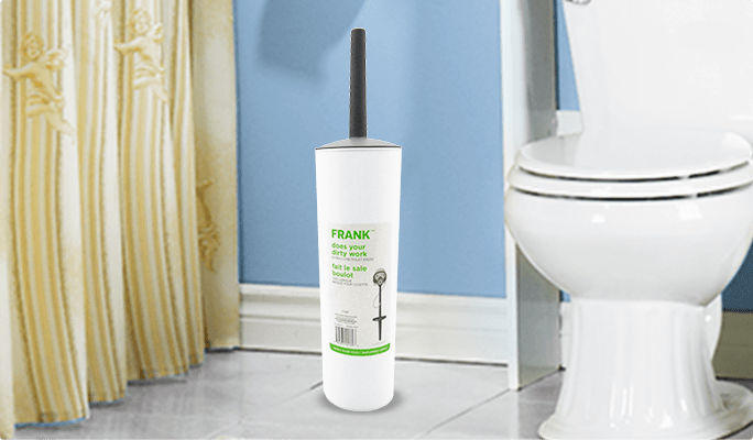 Une brosse à toilettes FRANK avec support à côté d'une toilette blanche. 