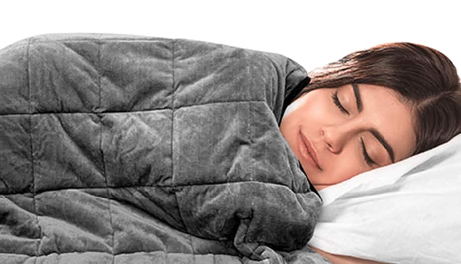 Woman sleeping under a grey weighted blanket. 