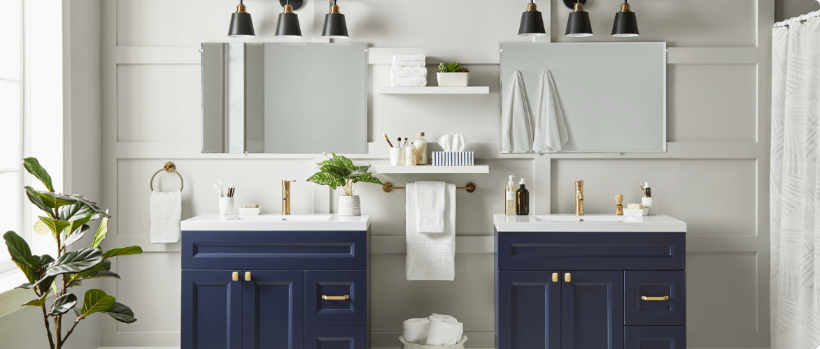 Bathroom with 2 navy canvas vanities, 2 wall-mounted mirrors, and 2 canvas black and bronze vanity lights.