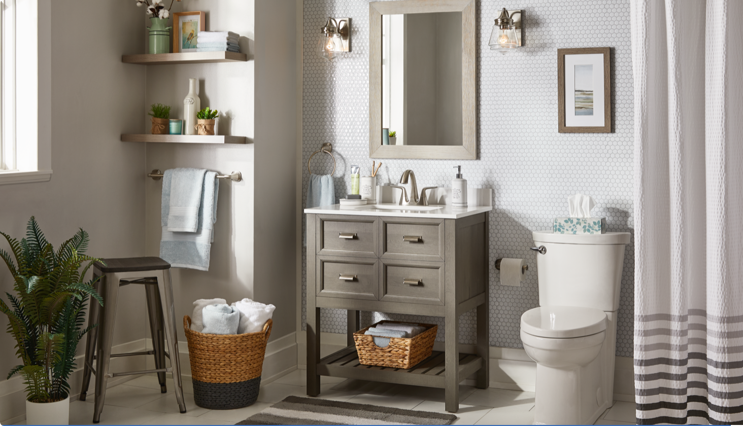 Salle de bain grise et blanche avec paniers à serviettes, rideaux de douche, plante verte et articles décoratifs.