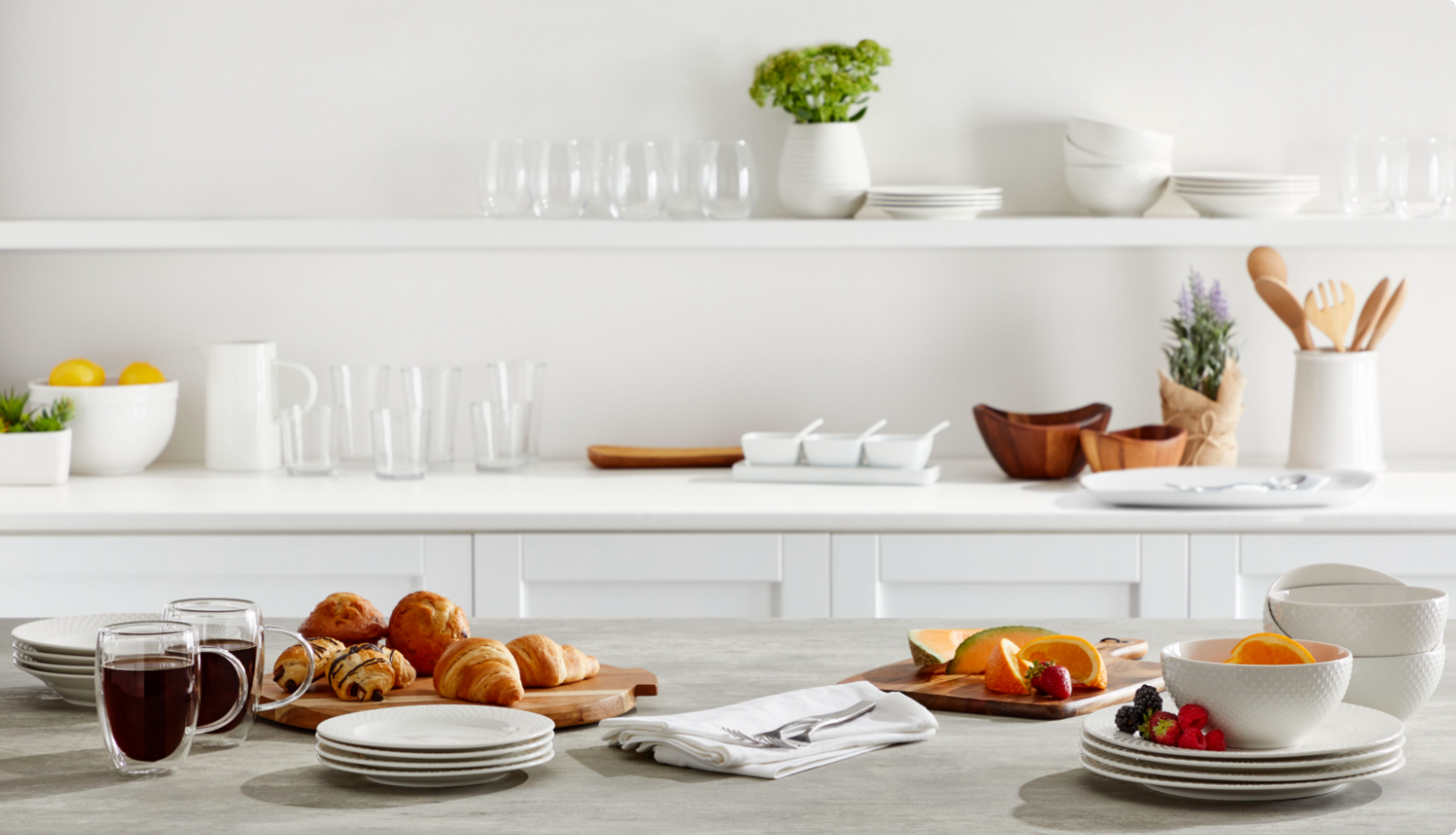 White kitchen with white serving dishes, glasses, and breakfast foods