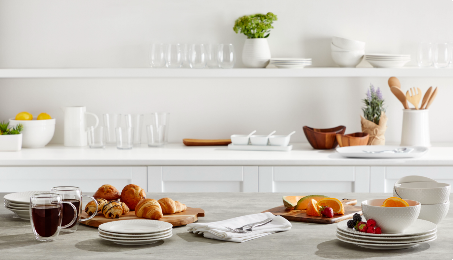 Cuisine blanche avec plats de service blancs, verres et aliments pour le petit-déjeuner.