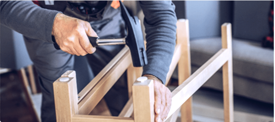 A man hammers a floor protector into the leg of a furniture item.