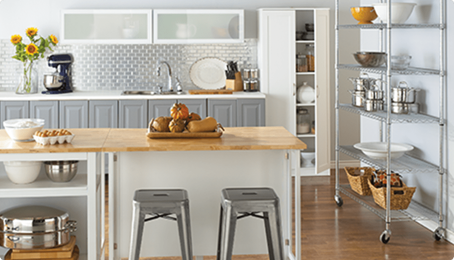 A kitchen with For Living 6-tier wire shelf with castors, kitchen island, and CANVAS bar stools.
