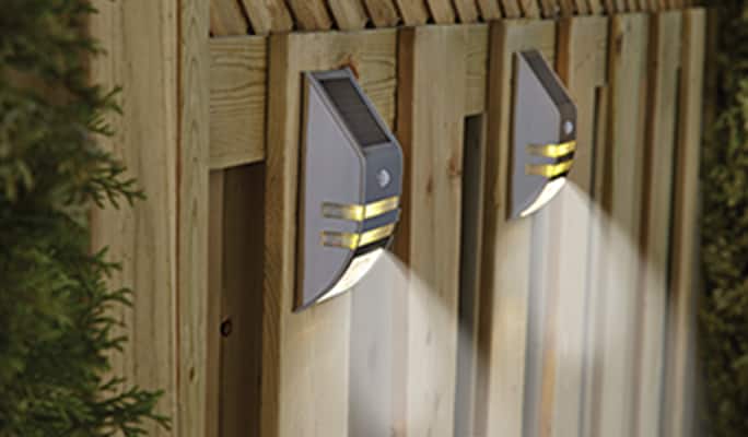 NOMA solar wall and deck lights on a wooden fence.