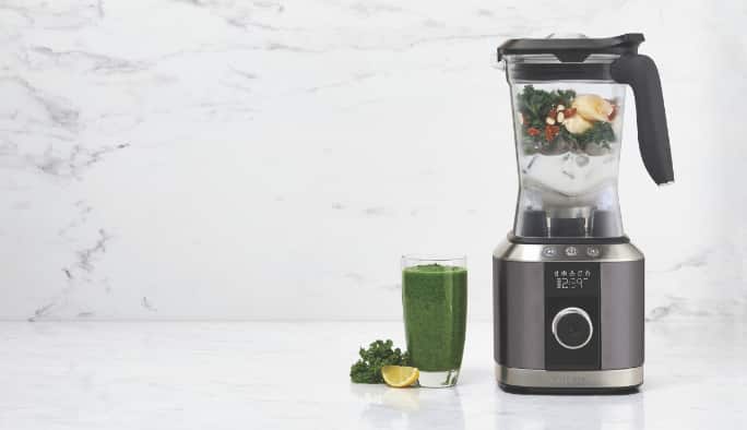 A blender with a glass of smoothie next to it.