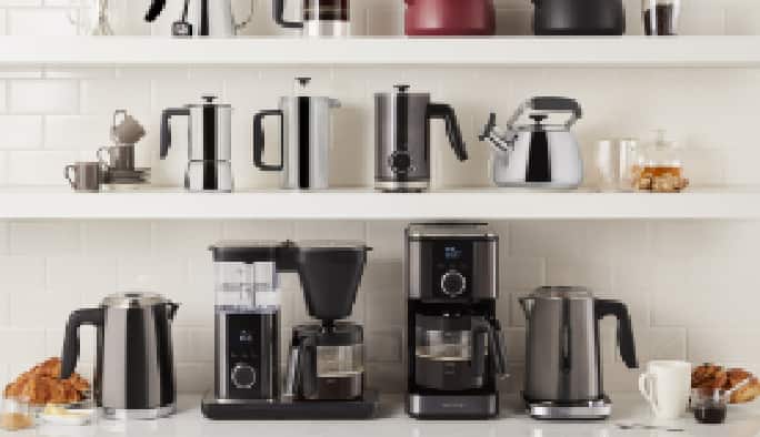 French press, kettles, espresso machine on kitchen counter and shelves. 