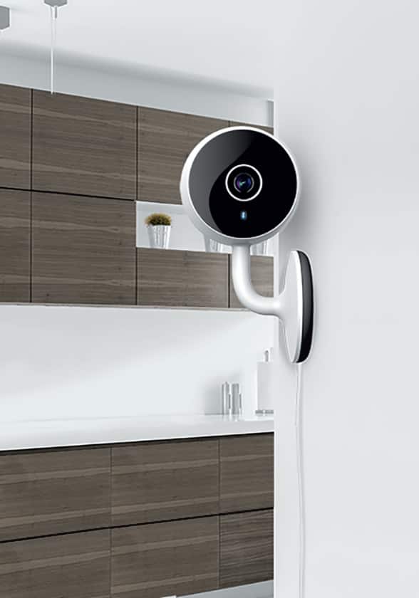 A smart security camera is attached to a wall inside a home.