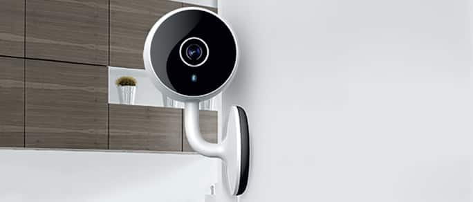 Une caméra de sécurité intelligente fixée à un mur dans une maison.