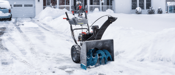 A two-stage snowblower in a freshly cleared driveway.