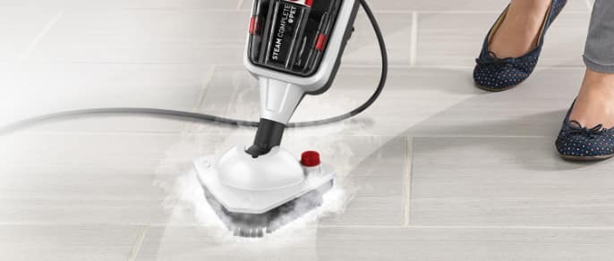 Woman uses a steam cleaner on a hardwood floor.