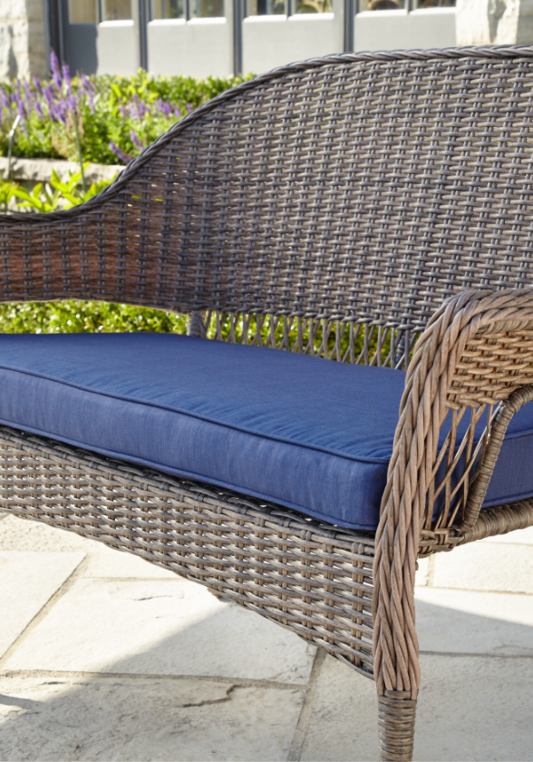 Close-up image of a wide, blue cushion designed for a patio loveseat.
