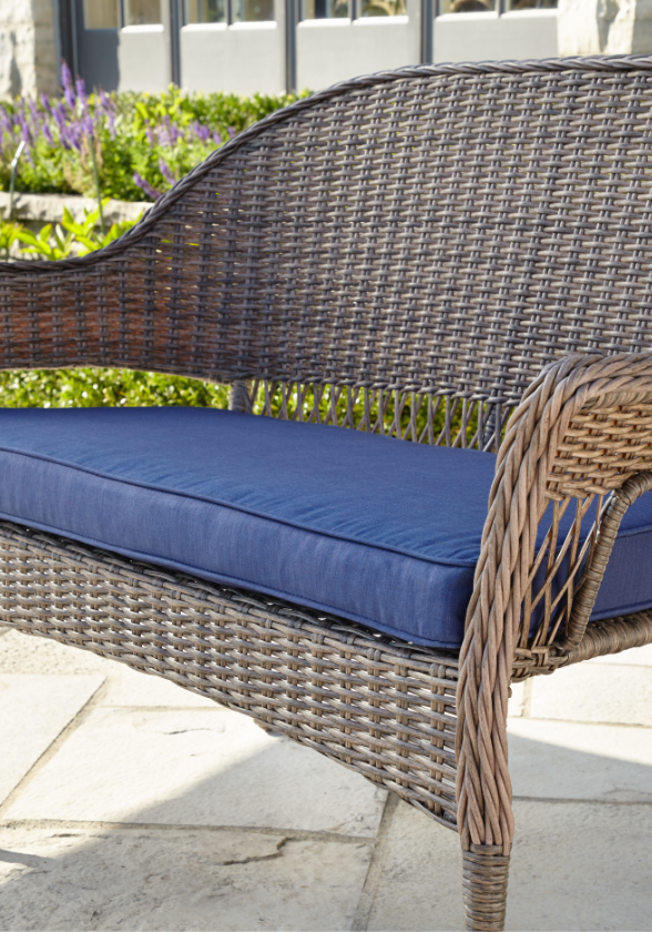 Gros plan d’un large coussin bleu conçu pour une causeuse de jardin