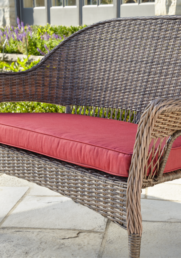 Gros plan d’un large coussin rouge conçu pour une causeuse de jardin 