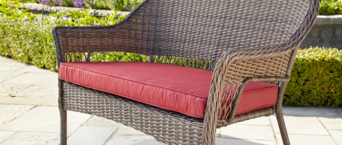 Close-up image of a wide, red cushion designed for a patio loveseat. 