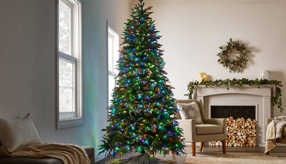 NOMA Advanced Aurora Music & Light Show Christmas Tree, 7.5-ft lit up in a room.