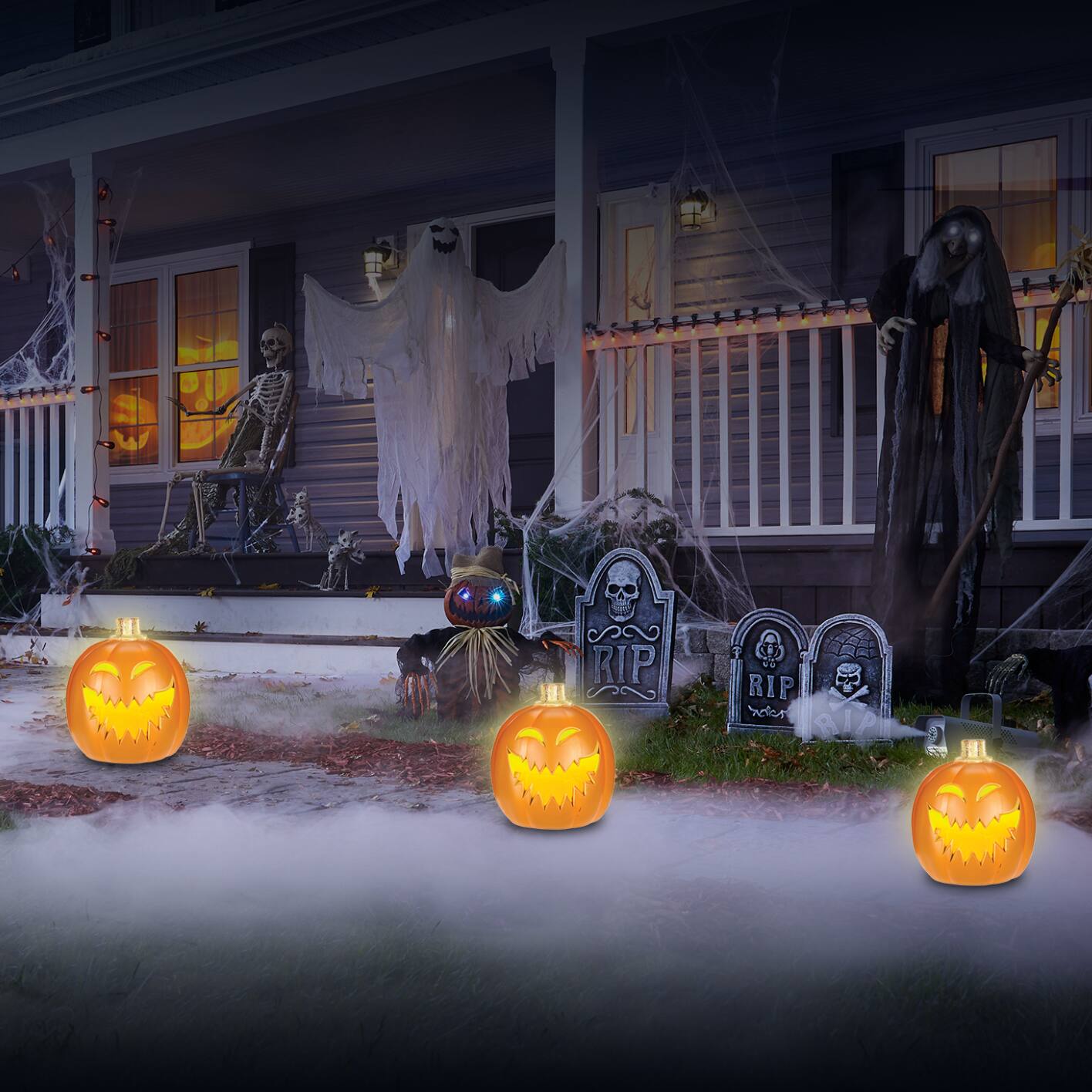 Scary Halloween porch decor with hanging ghost, lit up pumpkins, headstones and fog.