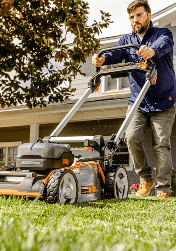 A man mowing grass in his lawn with a lawn mower. 