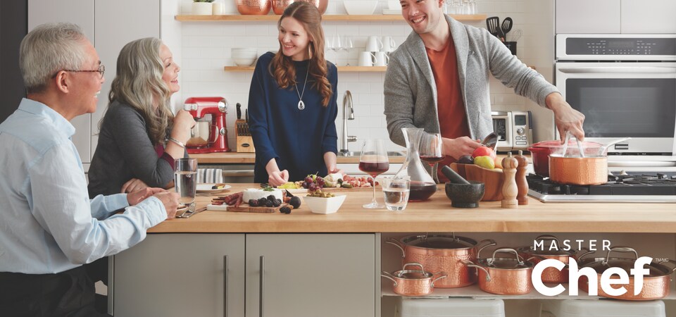 A group of 4 people cooking and eating around a kitchen island.